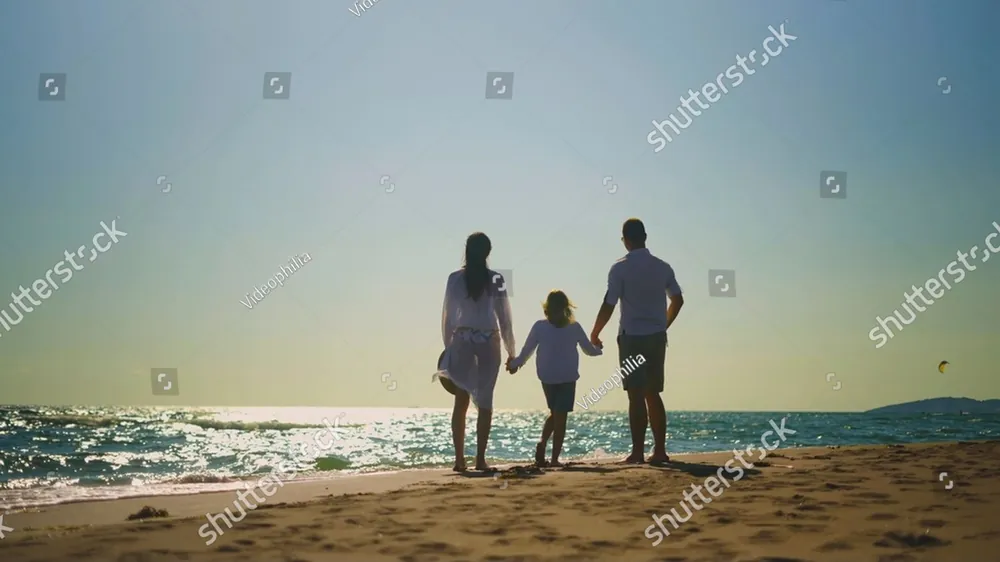 A family walking hand in hand on a beach at sunset