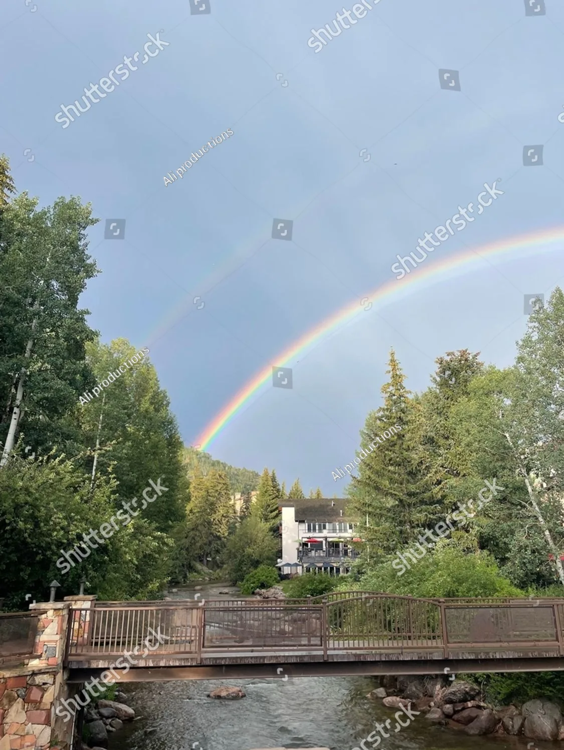 A rainbow over a creek and footbridge in the Colorado mountains